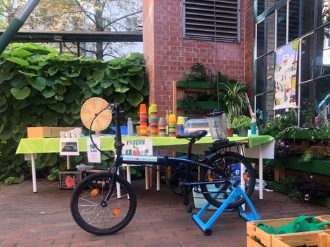 Ein Smoothiefahrrad steht auf einer Terasse, im Hintergrund ist ein Tisch mit bunten Trinkbechern zu sehen