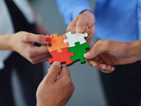 vier Hände halten Puzzle