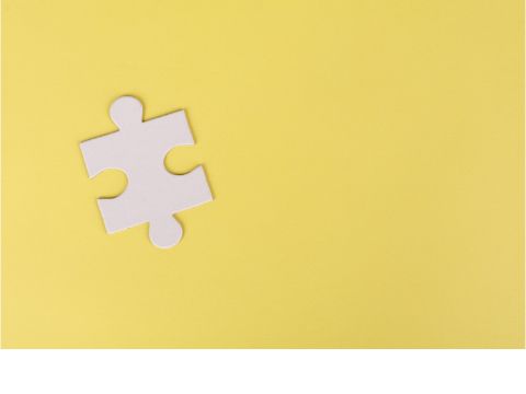 Ein Puzzlestein liegt auf einer gelben Fläche