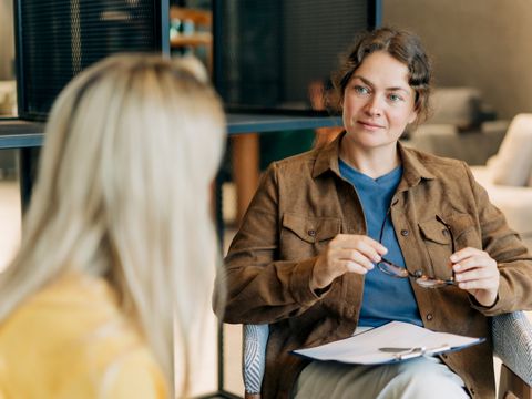 Eine Psychologin berät eine Klientin, während sie in ihrem Büro sitzt und aufmerksam zuhört und beobachtet.