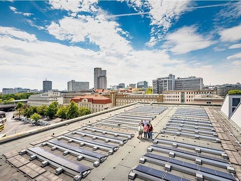 Solaranlage auf dem Dach, eine Gruppe von Personen guckt in die Kamera
