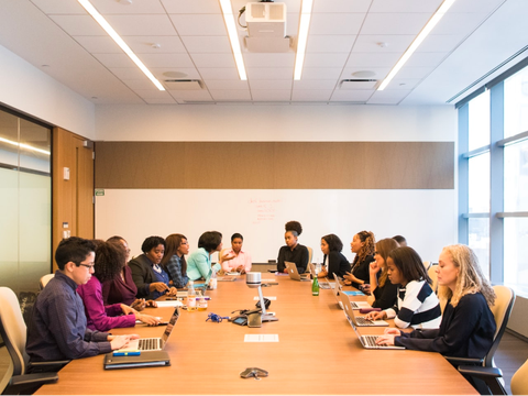 Beschäftigte eines Unternehmen sitzen an einem großen Tisch in einer Besprechung.