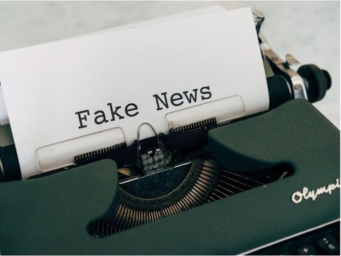 Sicht auf eine alte Olympia-Schreibmaschine, in der eine Blatt eingespannt ist, auf dem groß Fake News steht