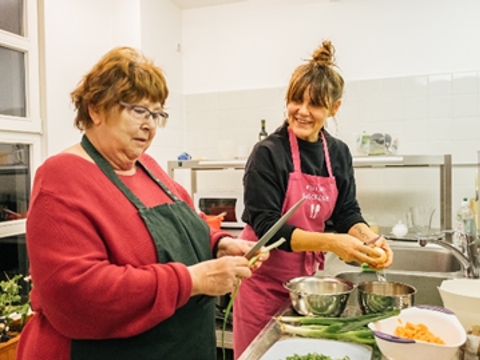 zwei Frauen schneiden Gemüse in einer Küche