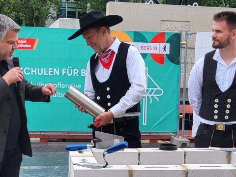 Schulstadtrat Andy Hehmke befüllt die Zeitkapsel bevor sie für Jahrzente im Grundstein für die Nachwelt eingemauert wird (Bild: Sabine Böhnig)