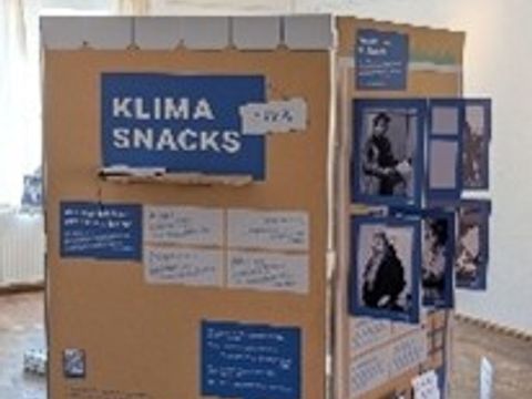 Eine Ausstellungswand zeigt viele verschiedene Bilder und Texte, zu lesen ist die große Überschrift "Klima Snacks"