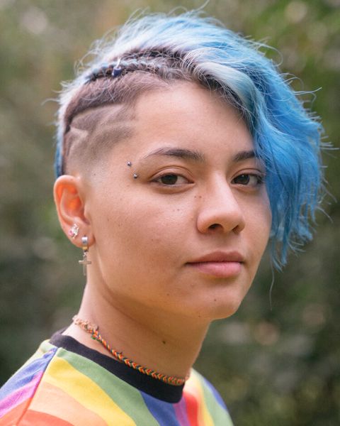 Junge Frau mit Undercut und blauen Haaren und Regenbogenhemd