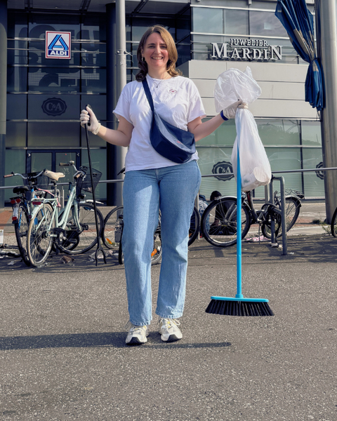 Eine Frau mit Mülltüten und Müllzange bei einem Clean Up in Gesudnbrunnen