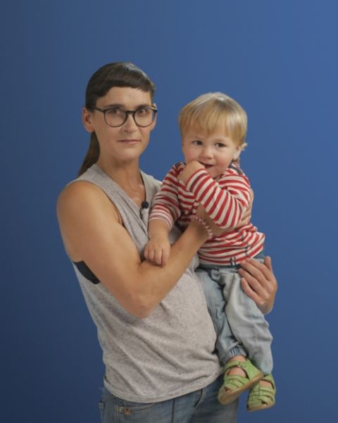 Auf dem Bild ist eine Alleinerziehende mit ihrem Sohn auf dem Arm in einer Interview Situation zu sehen