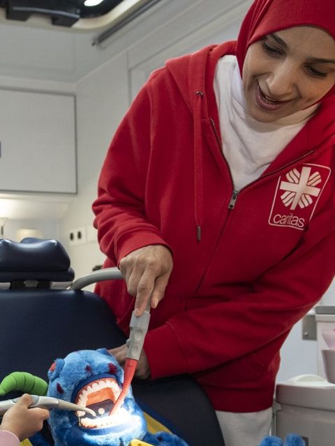 Kinder entdecken in dem riesigen Gebiss des Drachens Linda kleine Unebenheiten, die sie behandeln dürfen