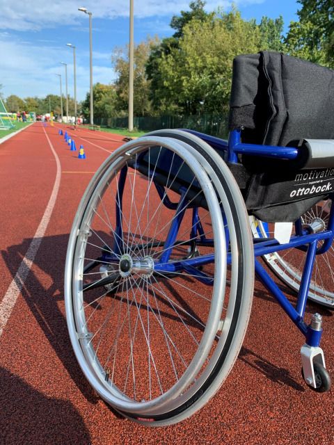 Rollstuhl von hinten auf einem Sportplatz