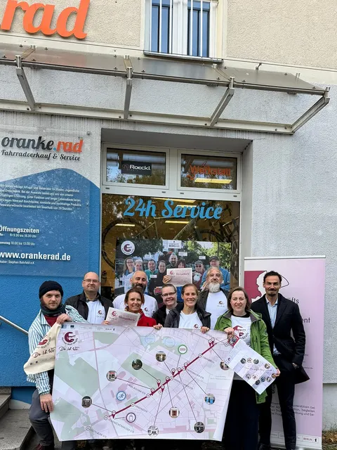 Gewerbetreibende aus der Konrad-Wolf-Straße und Mitarbeitende der Wirtschaftsförderung Lichtenberg posieren mit Stempelkarten und Faltplan