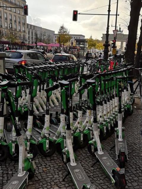 Absurd viele E-Scooter in Reihe. Im Hintergrund das Brandenburger Tor