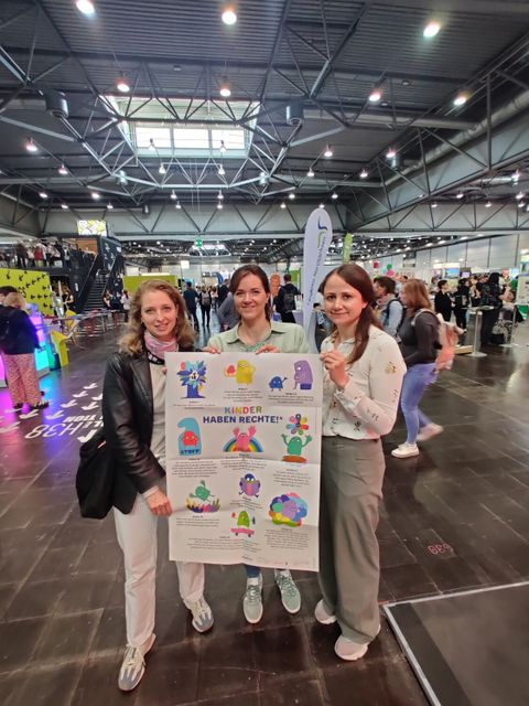 Hannah Böse (Kinder- und Jugendbeauftragte), Cindy Franke (Koordinatorin für Kinder- und Familienarmutsprävention) und Antonia Richter (Beteiligungskoordinatorin) mit dem Reinickendorfer Kinderrechteplakat (Bild: BA Rdf)