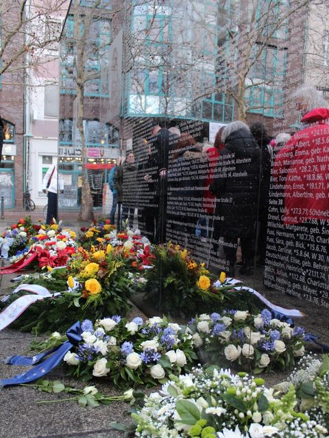 27. Januar 2025: Kränze und Blumen vor der Spiegelwand am Hermann-Ehlers-Platz