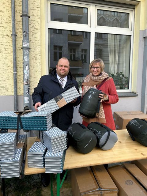 Sozialstadtrat Matthias Steuckardt (links) und Unionhilfswerksgeschäftsführerin Ulrike Hinrichs (rechts) verteilen Schlafsäcke vor der Wohnungslosentagesstätte des Unionshilfswerks in Schöneberg