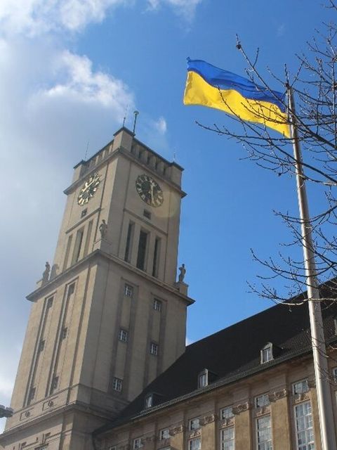 Die gehisste ukrainische Flagge vor einem Gebäude mit Turm