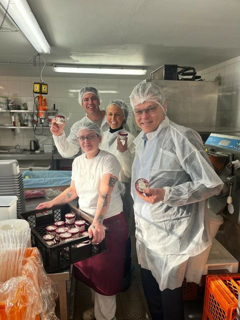 Vier Personen stehen in einer Produktionshalle und halten Eispackungen in den Händen.