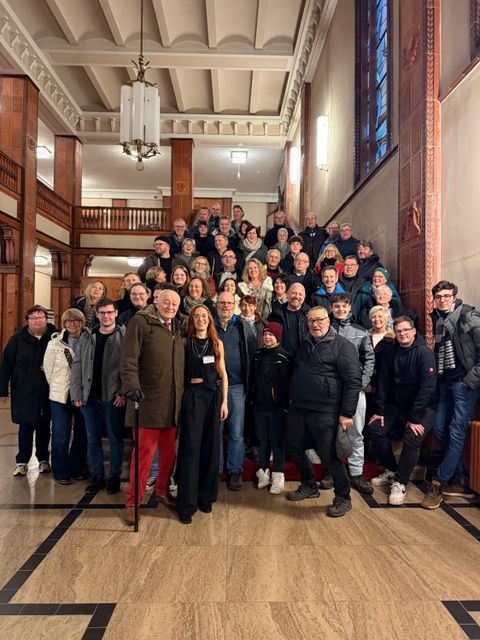 eine Gruppe von rund 50 Personen steht auf einer Treppe in einer großen Eingangshalle und freut sich, hier zu sein