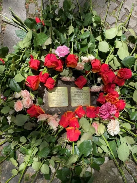 Verlegung der Stolpersteine für Zoya Gertrud und Hans Joachim Aqua-Kaufmann, 13.05.2023. Rosen liegen auf einem Gehweg um zwei Stolpersteine herum.