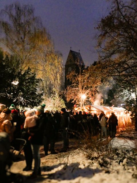 Menschen auf einem Weihnachtsmarkt im Licht von Lichterketten