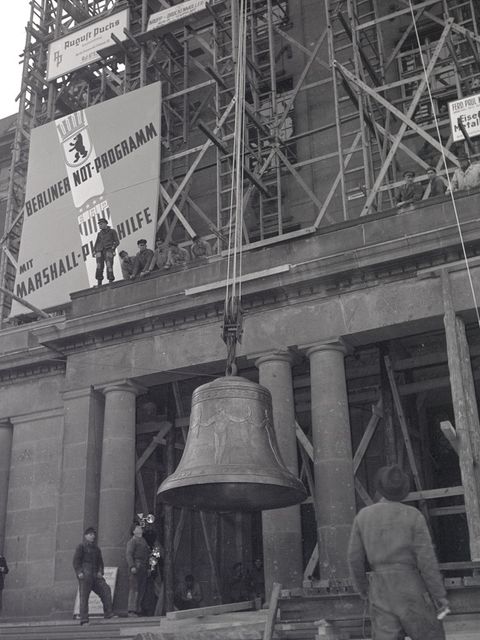 A large bell on a rope in front of a large building