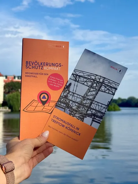 Hand hält die Flyer zum Bevölkerungsschutz und zum Stromausfall hoch