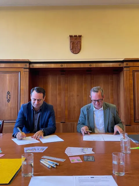 Staatssekretär Bozkurt (li) und Bezirksbürgermeister Igel (re.) unterzeichnen die Kooperationsvereinbarung