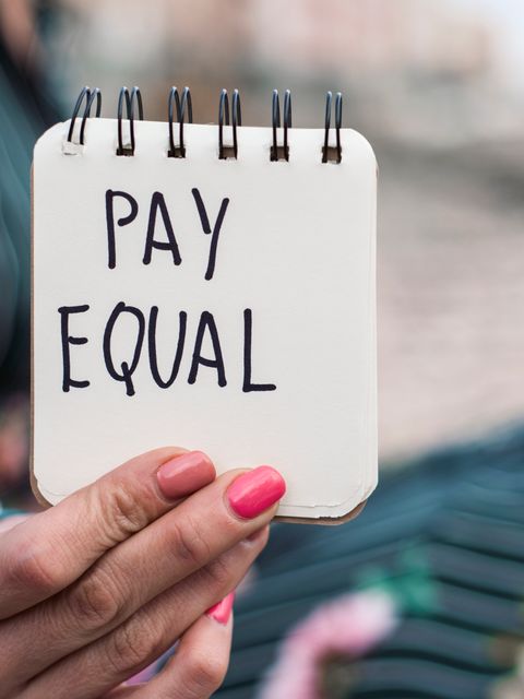 weibliche Hand hält Zettel mit Aufschrift Pay Equal