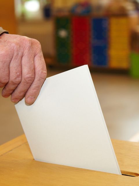 Stimmzettel wird in Wahlurne gesteckt