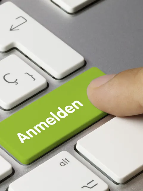 Ein Finger drückt auf eine grüne Taste an einer Tastatur. Auf der Taste steht: Anmelden.