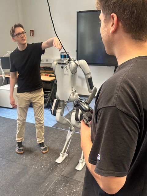 Zwei junge Männer präsentieren einen humanoiden Roboter