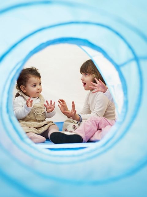 Baby und Kleinkind sitzen sich gegenüber