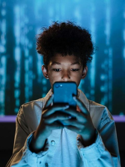 Kind schaut auf sein Handy vor einem blauen Matrix-Hintergrund