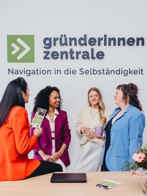 Vier Frauen reden und netzwerken vor dem Logo der Gründerinnenzentrale