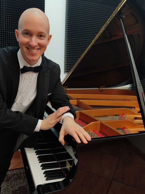 Ein Mann steht lässig am Klavier
