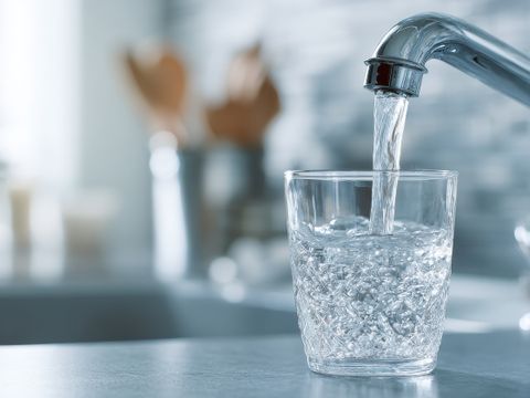 Ein Glas wird mit sauberem Wasser aus dem Küchenhahn gefüllt.