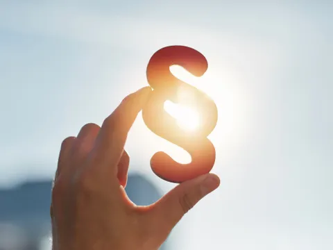 Hand hält Paragraphen Symbol in Sonne
