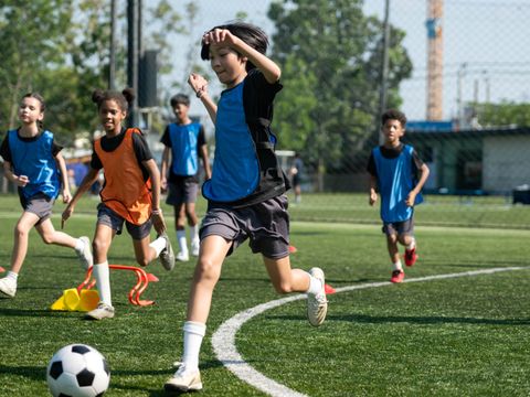 Kinder spielen Fußball auf einem Kunstrasenplatz