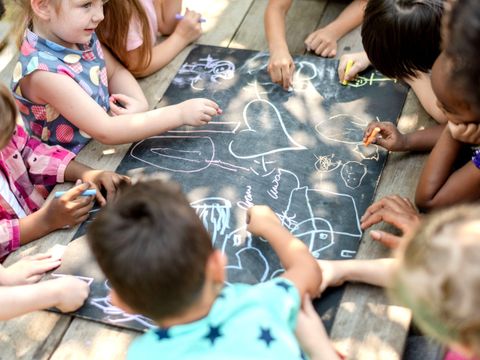 Kinder malen zusammen draußen mit Kreide.