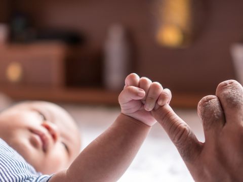 Neugeborenes Baby greift Finger von Erwachsenem
