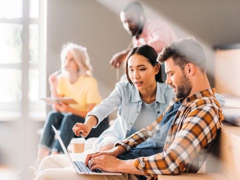Junge Studenten arbeiten zusammen am Laptop