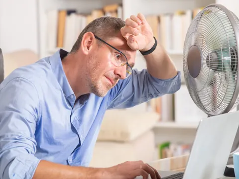 Mann leidet unter der Sommerhitze im Büro