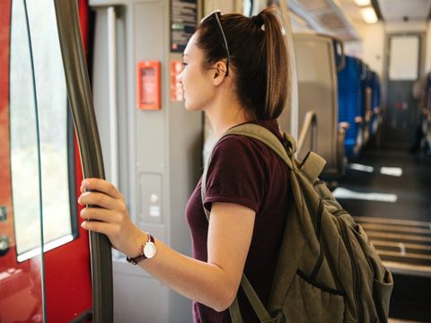Eine junge Frau mit Rucksack wartet darauf, dass der Zug hält, um auszusteigen
