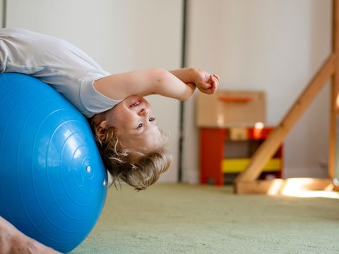 Porträt eines Kindes mit Zerebralparese bei der Physiotherapie in einem Kindertherapiezentrum. Ein Junge mit Behinderung absolviert therapeutische Übungen. Ein Kind mit besonderen Bedürfnissen erhält Physiotherapie.