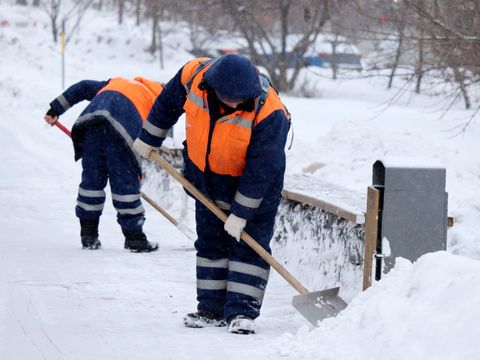 Männer in Arbeitskleidung schippen Schnee