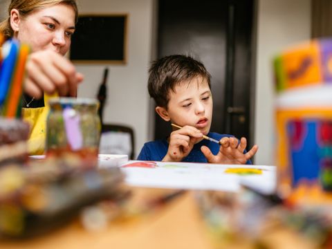Lehrerin malt gemeinsam mit einem Schüler mit Down-Syndrom