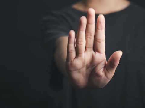 Nahaufnahme einer Hand, die nach vorne gehalten wird, als Signal für ‚Stopp‘ oder ‚Halt‘, vor unscharfem Hintergrund.
