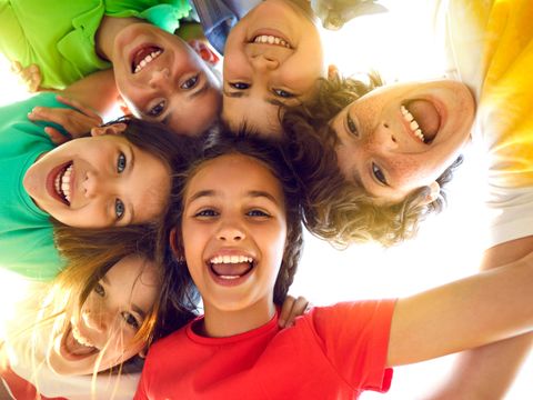 Group of happy little children playing together, having fun, huddling, looking down and smiling