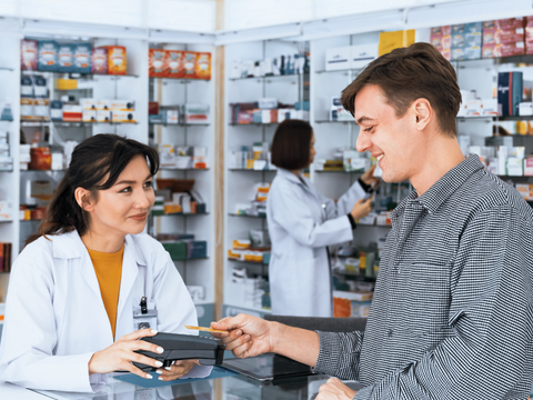 Kartenzahlung an einem Zahlungsterminal in einer qualifizierten Apotheke. Moderne bargeldlose Zahlung. Ein Kunde kauft in der Apotheke Medikamente gegen Rezept.